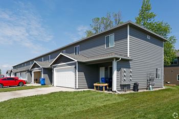 A home with a gray siding and a red car parked in the driveway